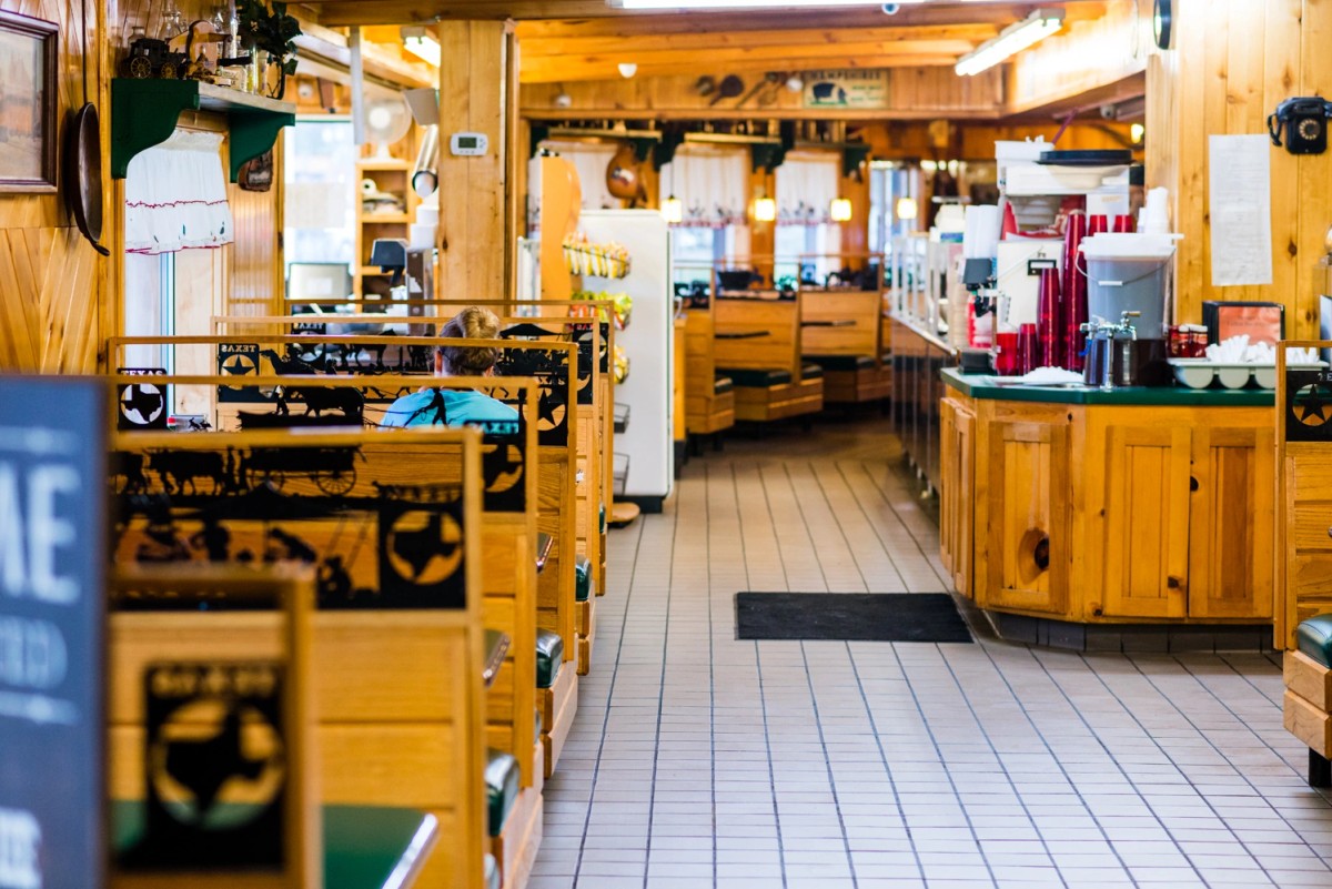 Wood-themed dining room at Stringer's Lufkin Bar-B-Q with booths and a seated guest